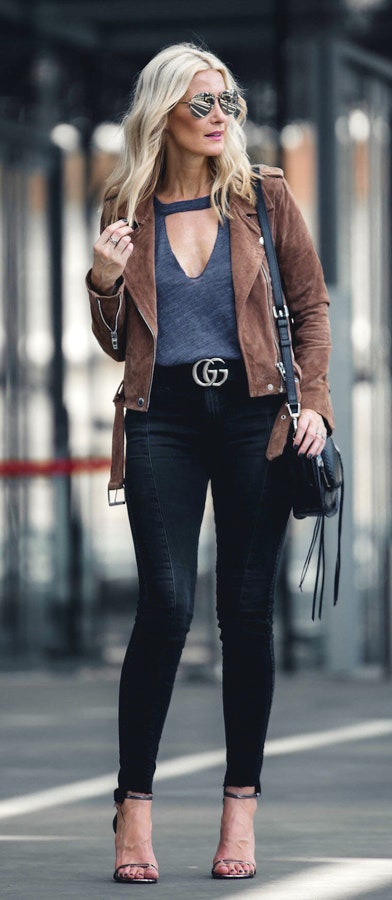 Women's brown framed sunglasses, gray top, brown blazer, black fitted jeans, pair of black open toe heels, and black crossbody bag.