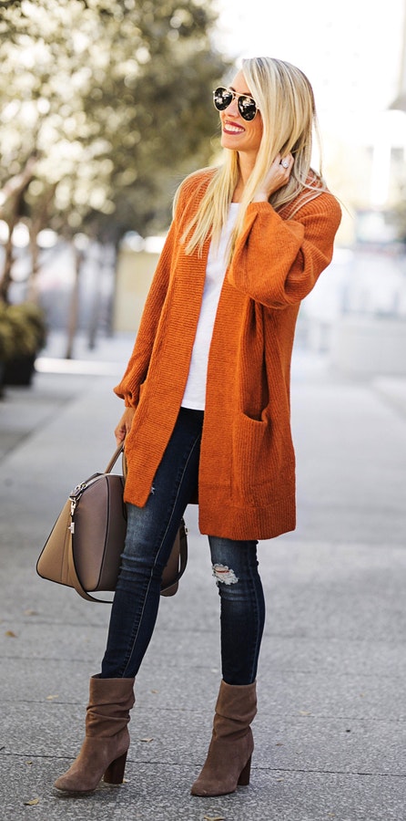 Women's orange cardigan with faded black jeans.